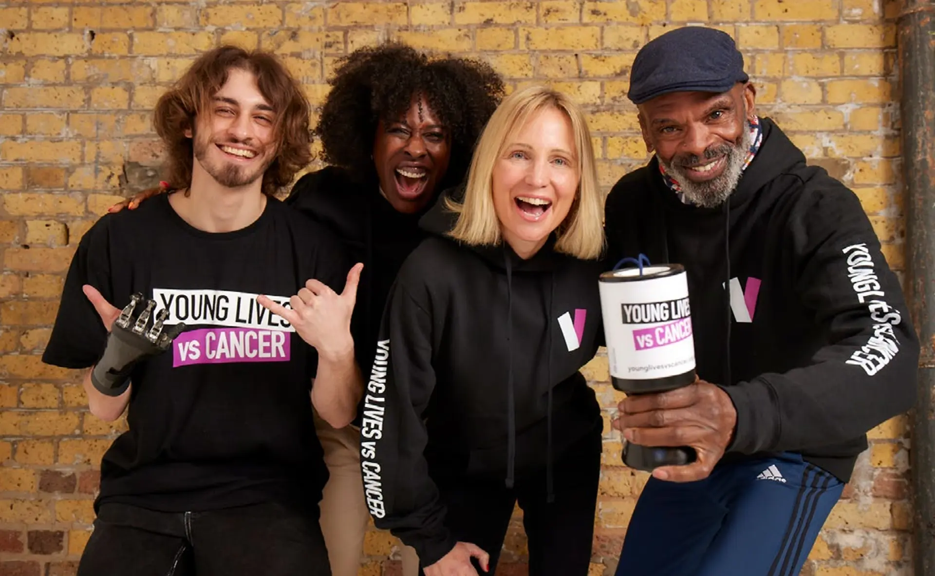 Four smiling Young Lives vs Cancer supporters with a charity collection tin